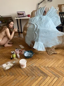 Weird home photo with a naked girl eating noodles in a Gollum-like pose