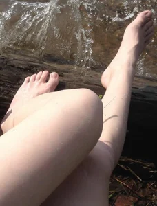 Young Candid Girl Sitting on the River Bank With Wet Feet