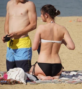 Sexy girl on the beach laying out and bending over in her bikini