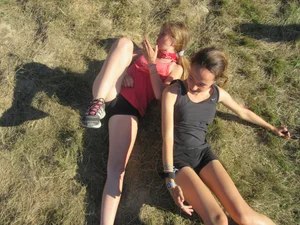 Couple of cute teens in shorts rolling on the grass laughing