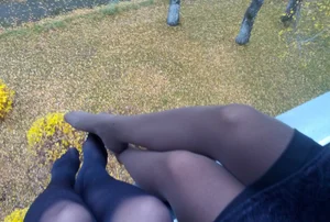Legs And Feet in Black Pantyhose of Two Teens Sitting on the Edge of a Roof
