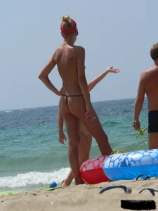 Topless skinny blonde lady in a g-string bikini at the beach