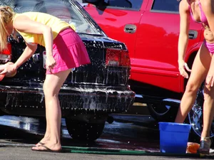 Group of cute girls at a car wash in bikinis and shorts
