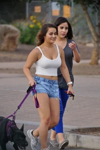 Sexy dog walker in shorts and tank top with friend in blue jeans