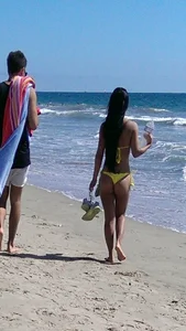 Beach babe with a nice ass and big tits in yellow thong bikini