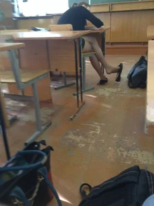 Skinny Teen Sitting in the Classroom With Crossed Legs in Pantyhose Playfully Swinging Her Shoe on Her Toe