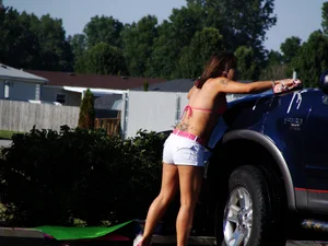Group of cute girls at a car wash in bikinis and shorts