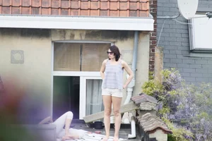Neighbor on rooftop tanning in bikinis