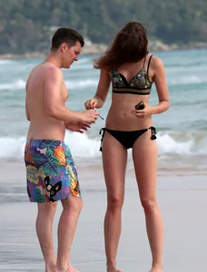Babe in black bikini on the beach with her boyfriend