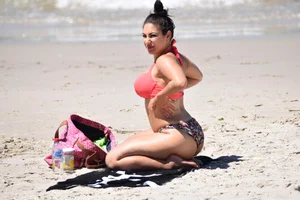 Huge boobed thick brunette babe on the beach in a bikini