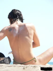 Topless beach milf looking sexy in a tiny g-string bikini