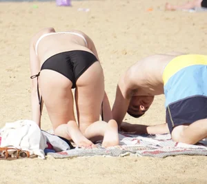 Sexy girl on the beach laying out and bending over in her bikini
