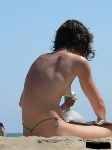 Topless beach milf looking sexy in a tiny g-string bikini