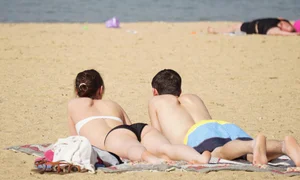 Sexy girl on the beach laying out and bending over in her bikini