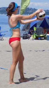 Skinny mature lady in red bikini bottom on the beach playing volleyball