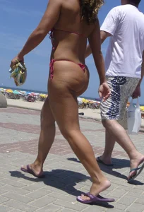 Big booty babe walking by the beach in thong