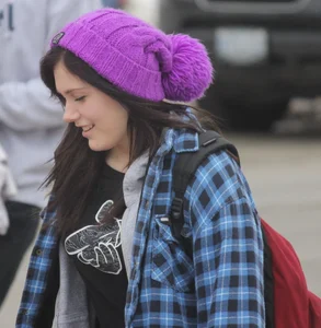 A cute brunette in leggings boots and hat