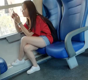 Two cute Asian teens on the bus in shorts showing their legs