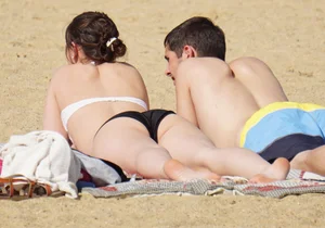 Sexy girl on the beach laying out and bending over in her bikini