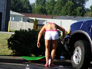 Group of cute girls at a car wash in bikinis and shorts