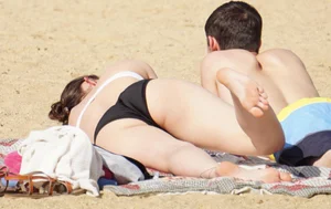 Sexy girl on the beach laying out and bending over in her bikini