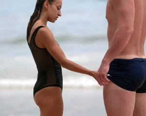 Skinny sexy lady on the beach in a black swimsuit