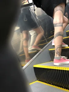 Girl in a Skirt With a Snake Tattoo on Her Leg Standing With Spread Legs on an Escalator Creepshots Series