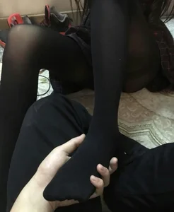Guy Holding a Foot of a Skinny Girl in Black Pantyhose in His Hand