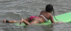 Brunette bikini girl on the beach and surfing in her bikini