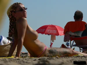 Topless tattooed lady at the beach with a nice ass in pink thong bikini