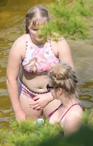 Chunky blonde enjoying some drinks in the water in her purple bikini