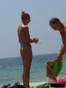 Topless skinny blonde lady in a g-string bikini at the beach