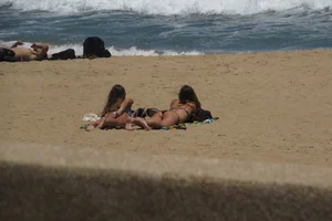 Two babes laying on the beach in bikinis with nice asses