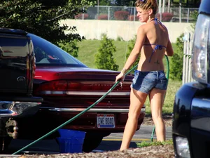 Group of cute girls at a car wash in bikinis and shorts