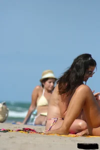 2 topless girls at the beach in thongs