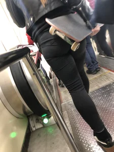 Sexy Round Ass in Tight Pants - Girl Holding a Skateboard on a Subway Escalator