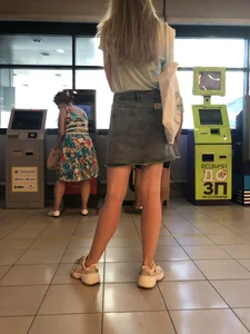 Young Candid Girl With Slim Pale Legs In a Denim Skirt Waiting in the Queue