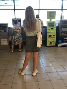 Young Candid Girl With Slim Pale Legs In a Denim Skirt Waiting in the Queue