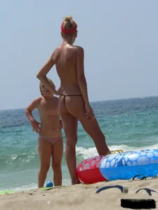 Topless skinny blonde lady in a g-string bikini at the beach
