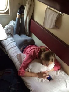 Sleeper train hottie in leggings and socks laying on her bench