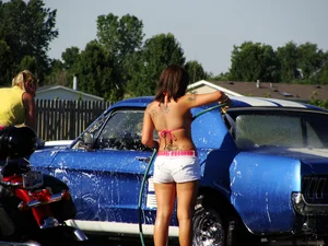 Group of cute girls at a car wash in bikinis and shorts
