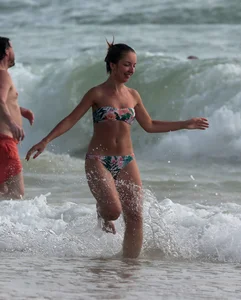 Cute skinny girl in a bikini at the beach playing in the water