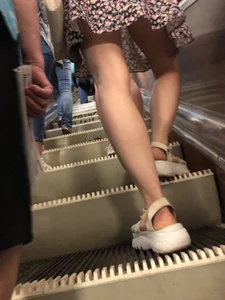 Candid Girl in Sandals and a Dress Standing With Spread Legs On the Subway Escalator