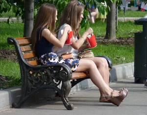 Girl in a Skirt and High Heeled Sandals Sitting on the Park Bench Candid