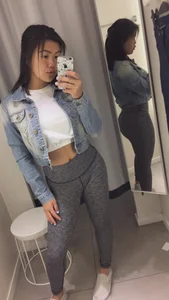 Asian girl in a top and yoga pants, mirror selfie in a fitting room