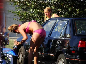 Group of cute girls at a car wash in bikinis and shorts