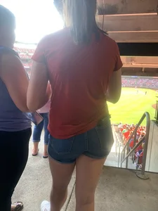 Bunch of girls in various outfits at a Cardinals baseball game
