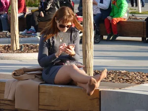 Milf in a Skirt and Pantyhose Sitting on the City Bench with Her Shoes Taken Off
