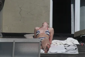 Neighbor on rooftop tanning in bikinis