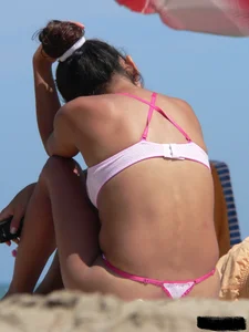Hot brunette ethnic girl on the beach in a pink thong bikini